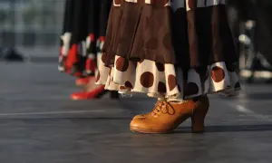 Taconeo flamenco: un zapato de cuero marrón con cordones y tacón, parte de un vestido de lunares, listo para bailar.