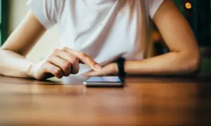 Dłoń dotyka ekranu telefonu, szukając informacji, jak zresetować telefon Redmi.
