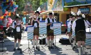 Blaskapelle spielt beim Taufkirchen Volksfest. Musiker in Tracht mit Hüten und Federn spielen Trompeten und Hörner.