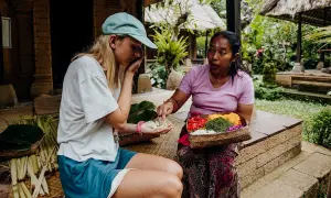 Une touriste apprend à faire des offrandes avec sa guide à Bali.