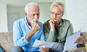 Zamyśleni seniorzy analizują dokumenty, szukając informacji, jak zapisać mieszkanie w testamencie wzór.