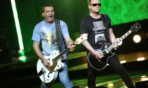 Lady Pank gra "Zamki na piasku". Muzycy na scenie z gitarami, jeden w koszulce z orłem, drugi w czarnej z cylindrem.
