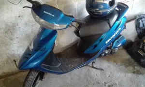 Niebieski skuter Honda Dio z niebieskim kaskiem ozdobionym płomieniami.