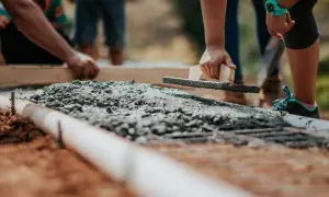 Pracownicy wyrównują świeży beton kielnią. Zastanawiasz się, ile kosztuje metr sześcienny betonu?