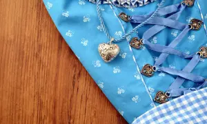 Ein Dirndl-Mieder mit Herzanhänger und Schnürung liegt auf Holz. Bald wird die Dirndlschürze gewaschen.