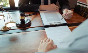 Prawnik wskazuje na dokument, omawiając sytuacje, kiedy odrzucenie spadku jest nieskuteczne. Waga sprawiedliwości i młotek sędziowski symbolizują prawo.