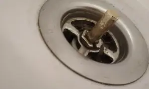 Widoczny jest zepsuty korek odpływu w wannie zabudowanej, gotowy do wymiany.