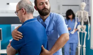 Fizjoterapeuta pomaga pacjentowi z bólem pleców w nocy i nad ranem.