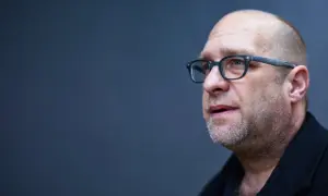 Portret mężczyzny w okularach, łysiejącego, z zarostem. Todd Hido w skupieniu.