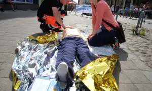 Ćwiczenia pierwszej pomocy: pozycja czterokończynowa przy omdleniu na kocu termoizolacyjnym.