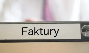 Segregator z napisem "Faktury" na biurku, gotowy do uporządkowania dokumentacji.