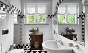 Un elegante bagno bianco e nero vintage con piastrelle a scacchi, un lavabo classico e un vaso di ortensie.