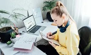 Kobieta pracuje nad CV, szukając pracy. Na biurku laptop z napisem "Job Search", kalendarz i notatnik.