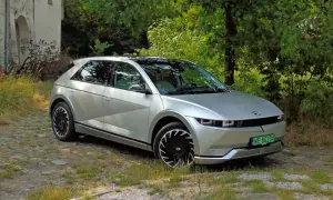 Srebrny Hyundai Ioniq 5 na tle zarośli i starego budynku.