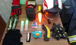 Na stole rozłożony sprzęt strażacki: rękawice, latarki, kask, nóż, raczki, kombinezon. Znajomość nazw sprzętu strażackiego jest kluczowa.