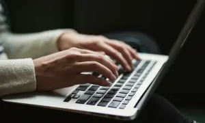Dłonie piszą na laptopie, szukając informacji o antimalware service executable co to jest i jak działa.