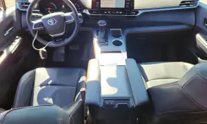 Wnętrze Toyoty Sienna Hybrid: czarne skórzane fotele, kierownica, deska rozdzielcza z ekranem nawigacji.