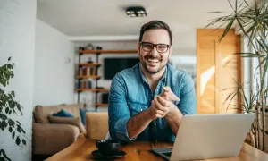 Hombre sonriente con portátil, buscando ideas para negocios rentables en un pueblo.