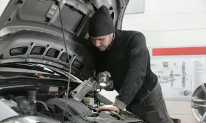Mechanik bada przyczyny nagłego spadku mocy silnika powyżej 3000 obrotów, oświetlając silnik latarką.