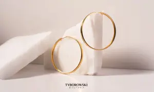 Złote kolczyki koła na tle białych kamieni. Nawet przy najwyższej cenie srebra w historii, te klasyki zawsze błyszczą.