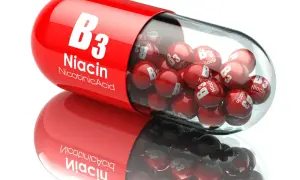 Czerwona kapsułka wypełniona małymi kulkami z napisem "Niacin B3". To niacynobaza w pigułce.