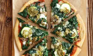 Pyszna pizza ze szpinakiem, cukinią i pieczarkami, polana zielonym pesto. Idealna na lekki obiad.