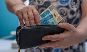 Dłonie chowają banknoty 50 zł do czarnego portfela. To może być początek oszczędzania na emeryturę, jak w funduszu Amundi Stars Silver Age.