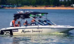 Łódź motorowa z pasażerami płynie po wodzie, tworząc pianę. Na burcie widnieje napis "Marina Domaniewska".