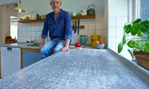 Man sitter på en köksbänk med en betongskiva som är behandlad för att få en unik textur.