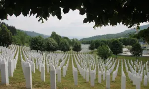 Enormt fält med vita gravstenar, en påminnelse om folkmordet i Srebrenica. Grönskande kullar i bakgrunden.
