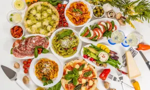 Obfity tradycyjny włoski obiad: pizze, makarony, sałatka caprese, wędliny, warzywa i ser.