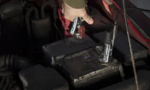 Ręka podłącza kable do akumulatora, przygotowując odpalanie motocykla na kable.