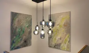 Moderne Hängelampen montieren über einem Treppenaufgang, flankiert von abstrakter Kunst.