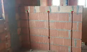 Przygotowanie ścian do instalacji elektrycznej: widoczne bruzdowanie pod kable w ceglanej ścianie, z widocznymi puszkami instalacyjnymi.