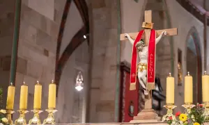 Chrystus na krzyżu z czerwoną wstęgą "Alleluja". Obok płonące świece. 25 marca święto kościelne.