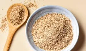 Eine Holzschale und ein Löffel gefüllt mit Haferkleie. Haferkleie ist ein nährstoffreiches Nebenprodukt der Haferverarbeitung.
