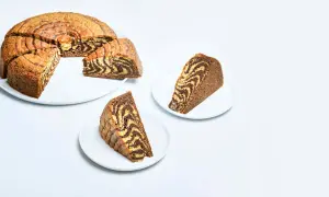 En saftig tigerkaka med vackra mönster, perfekt för ett enkelt tigerkaka recept. Två skivor serveras på vita fat.