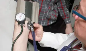 Lekarz mierzy ciśnienie. Pamiętaj o terminach dostarczenia L4 do ZUS po ustaniu zatrudnienia.