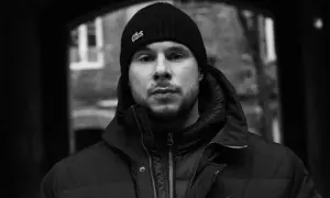 Portret młodego mężczyzny w czapce z logo Lacoste, jednego z wielu polskich raperów, który tworzy muzykę uliczną.