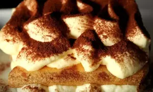 Un délicieux tiramisu au marsala, garni de cacao, avec des couches de crème onctueuse et de biscuits savoyards.
