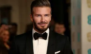 Uomo con impeccabili capelli all'indietro, barba curata e smoking nero con papillon.