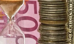 Klepsydra i stos monet na tle banknotu 500 euro. Czy numizmaty co to, to tylko monety?