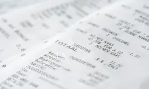 Zbliżenie na paragony z widocznymi nazwami produktów, cenami i sumą całkowitą.