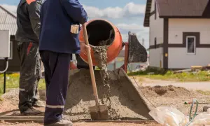 Robotnicy mieszają beton. Widać, ile piasku na kubik betonu jest potrzebne do uzyskania odpowiedniej konsystencji.