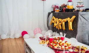 Złote balony z napisem "PARTY" i przekąski na stole tworzą atmosferę wieczoru panieńskiego w domu.