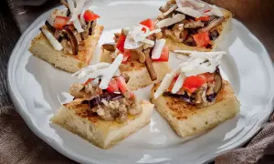Deliziosi crostini con melanzane, pomodoro e scaglie di formaggio su pane tostato.