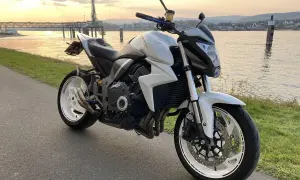 Biały motocykl turystyczny Honda zaparkowany nad rzeką o zachodzie słońca.
