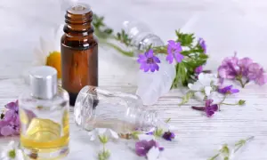 Aromaterapia: amol na co pomaga? Butelki z olejkami i kwiaty sugerują relaks i ukojenie.