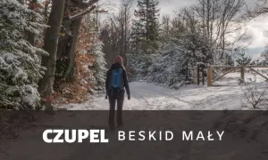 Kobieta z plecakiem idzie zimowym szlakiem w Beskidzie Małym. To czupel najładniejszy szlak, pokryty śniegiem.
