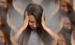 Vrouw met handen op haar hoofd, gezicht vertroebeld, wat de mentale kater na alcohol symboliseert.